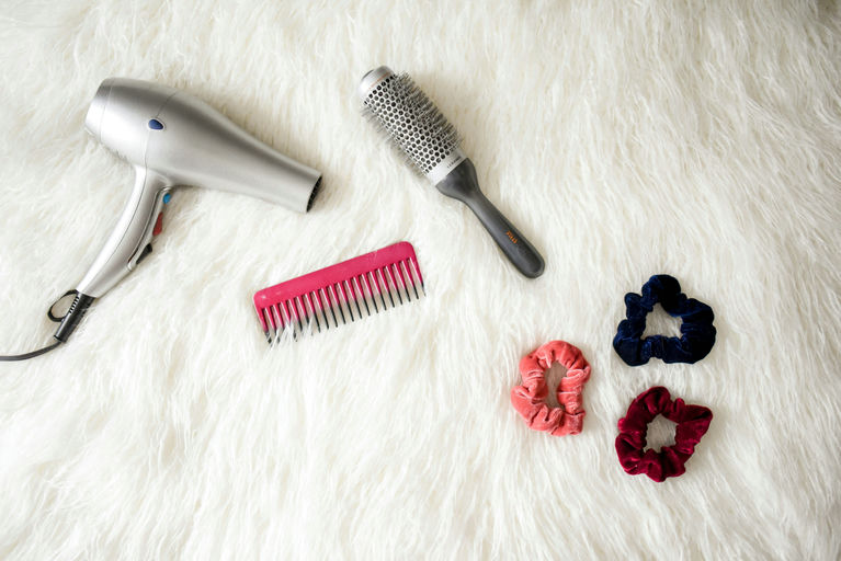 Woman using high-quality hair appliances, such as a straightener and curler, for proper hair care and styling at home