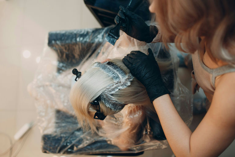 Woman using a hair straightener on long, sleek hair in a modern bathroom setting, demonstrating professional styling techniques